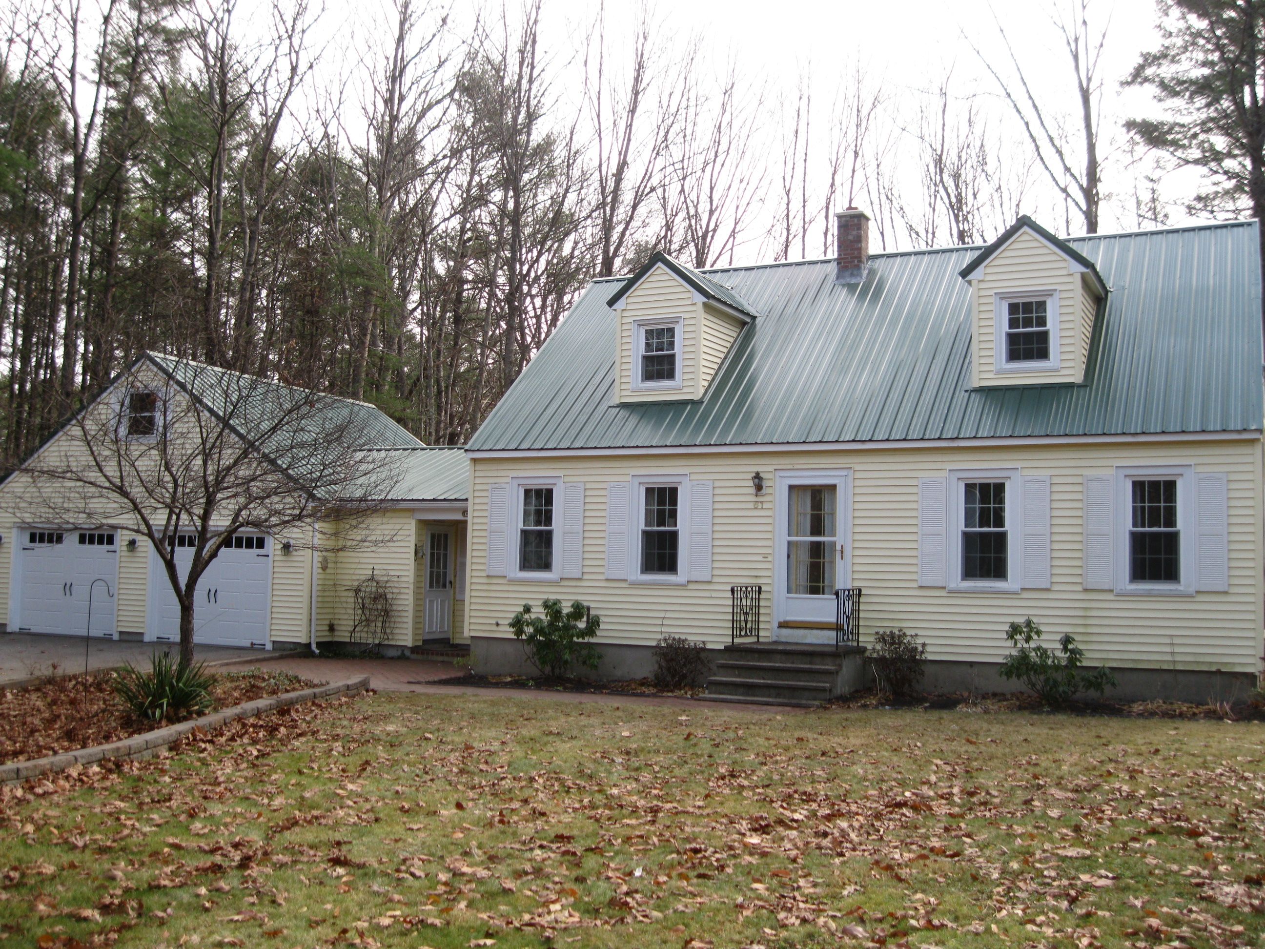 A green metal roof on a yellow cape with a barn