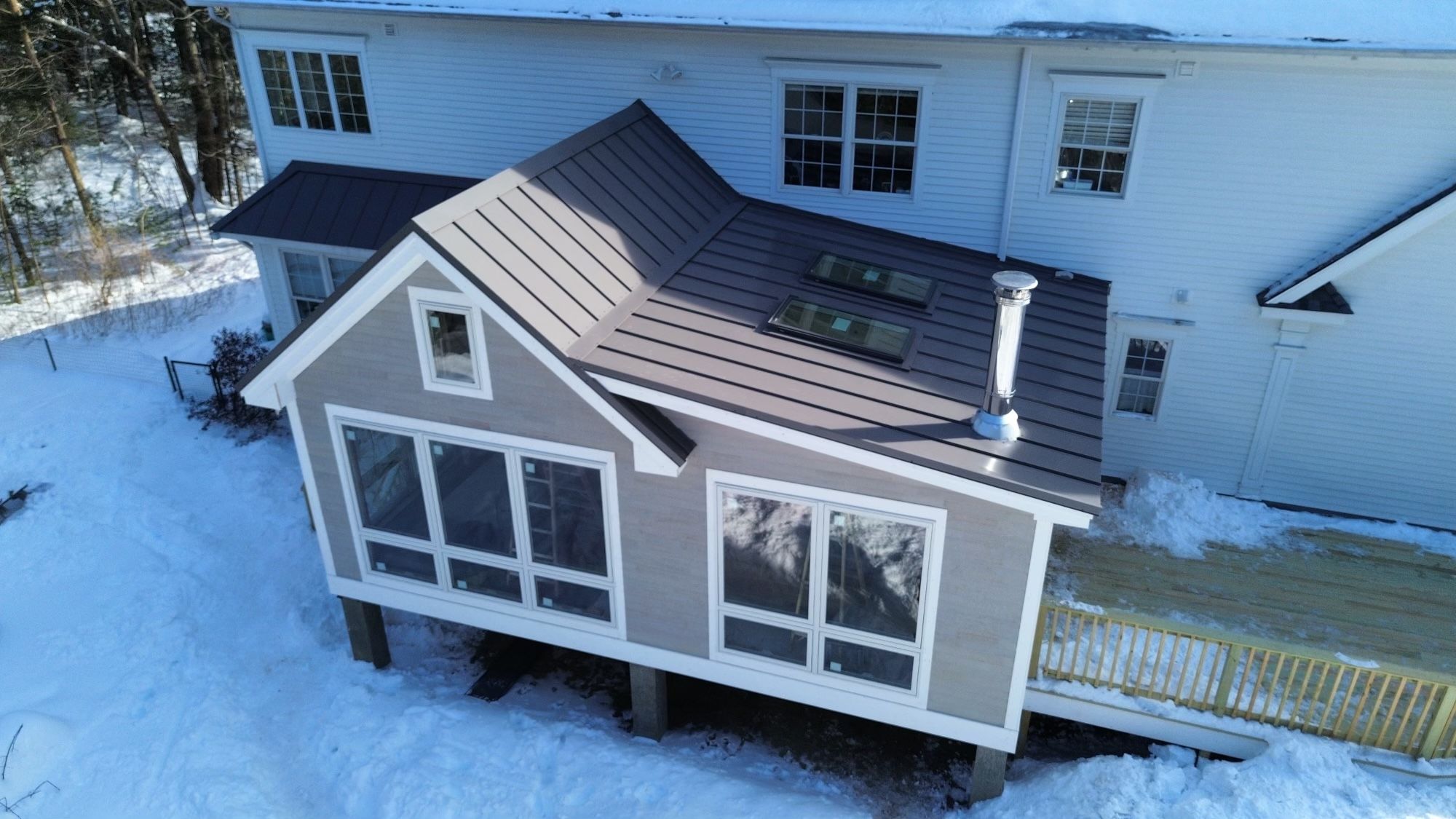 A finished metal roof Superior Roofing put on a sunroom addition, with snow on the ground