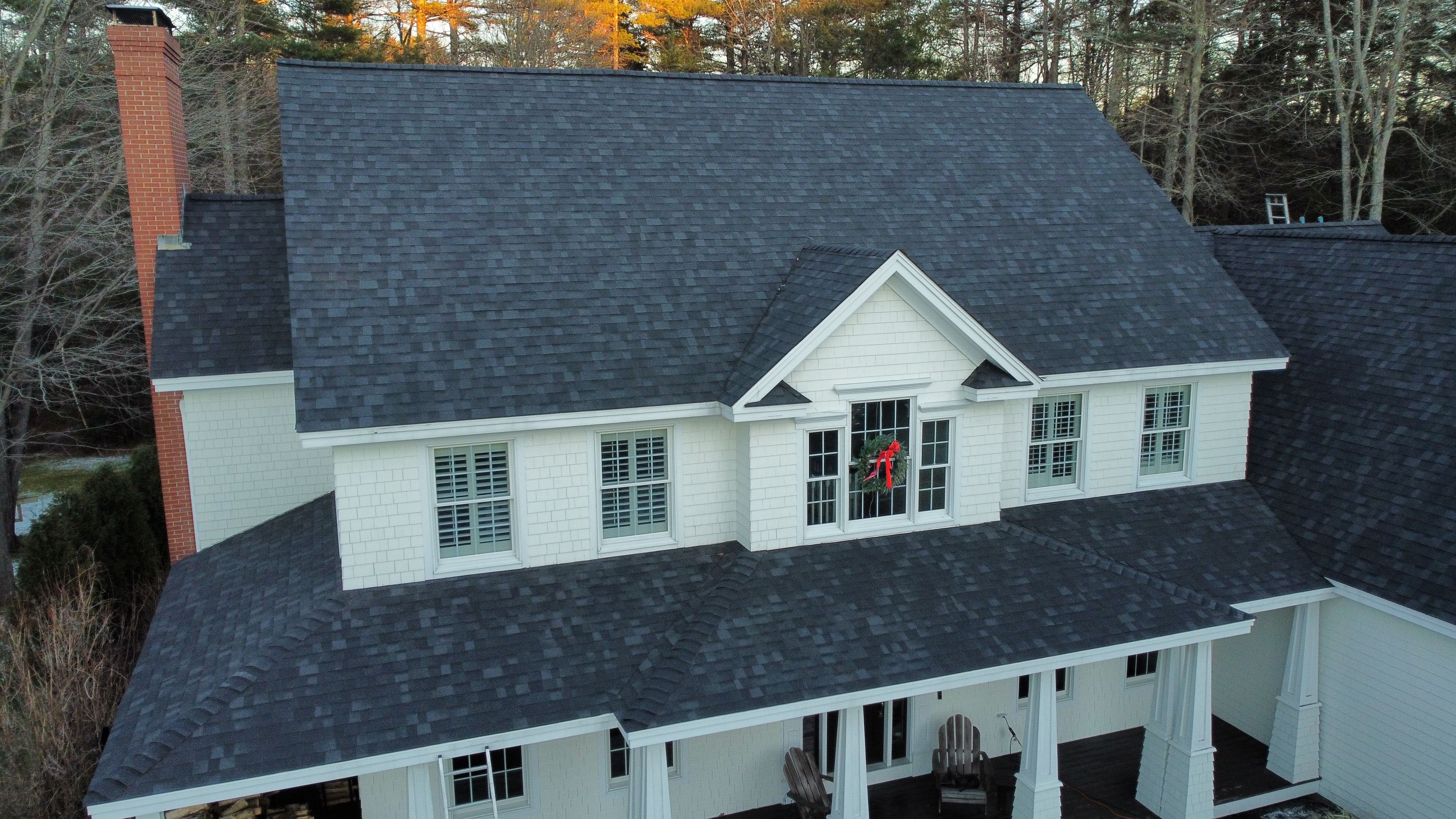 A new charcoal shingle roof on a white colonial with dormers