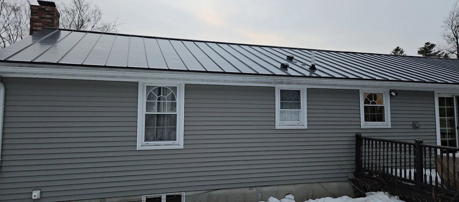 A new dark standing seam metal roof on a gray house