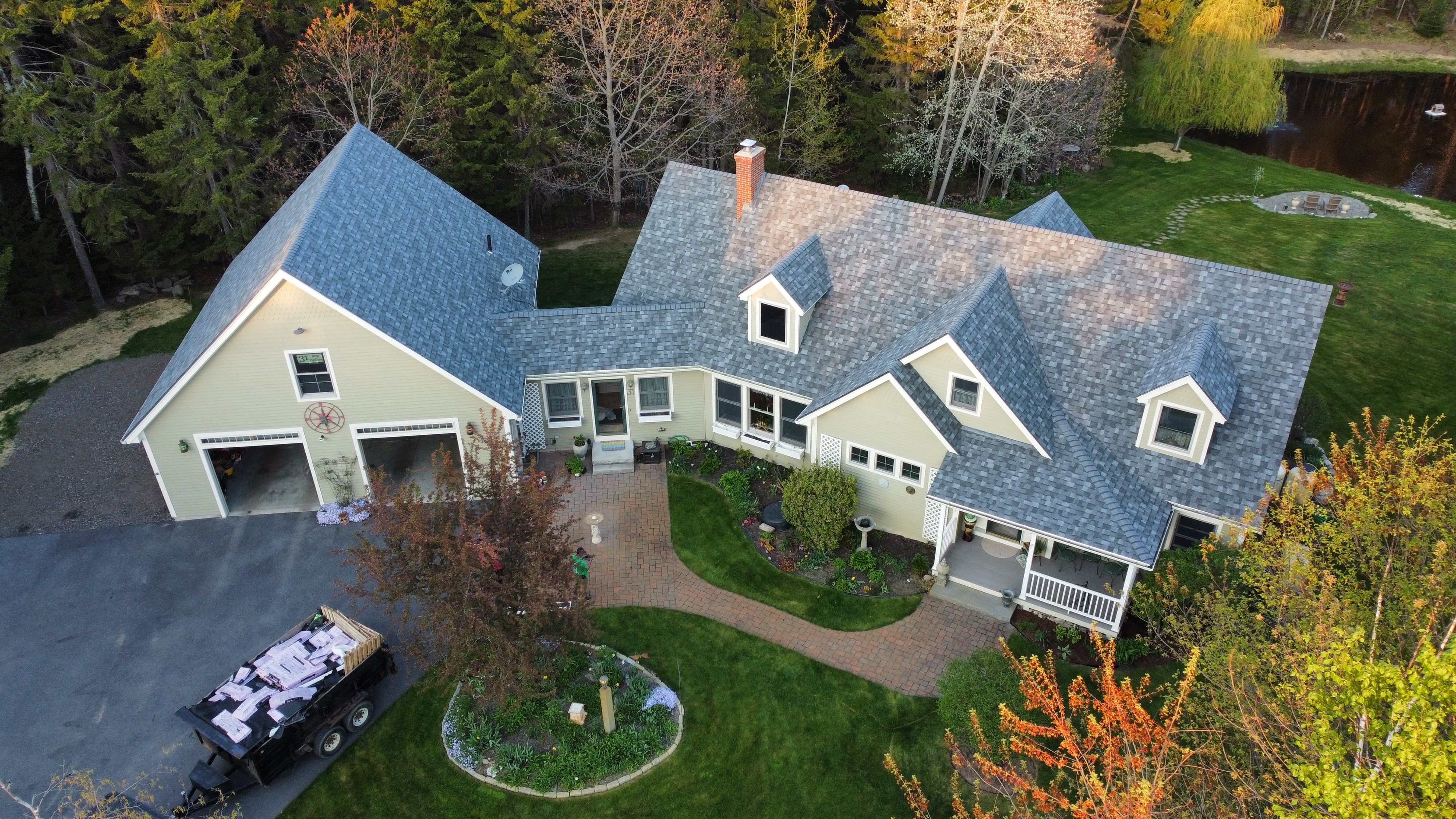 A new gray shingle roof on a cedar-shingled house with decks