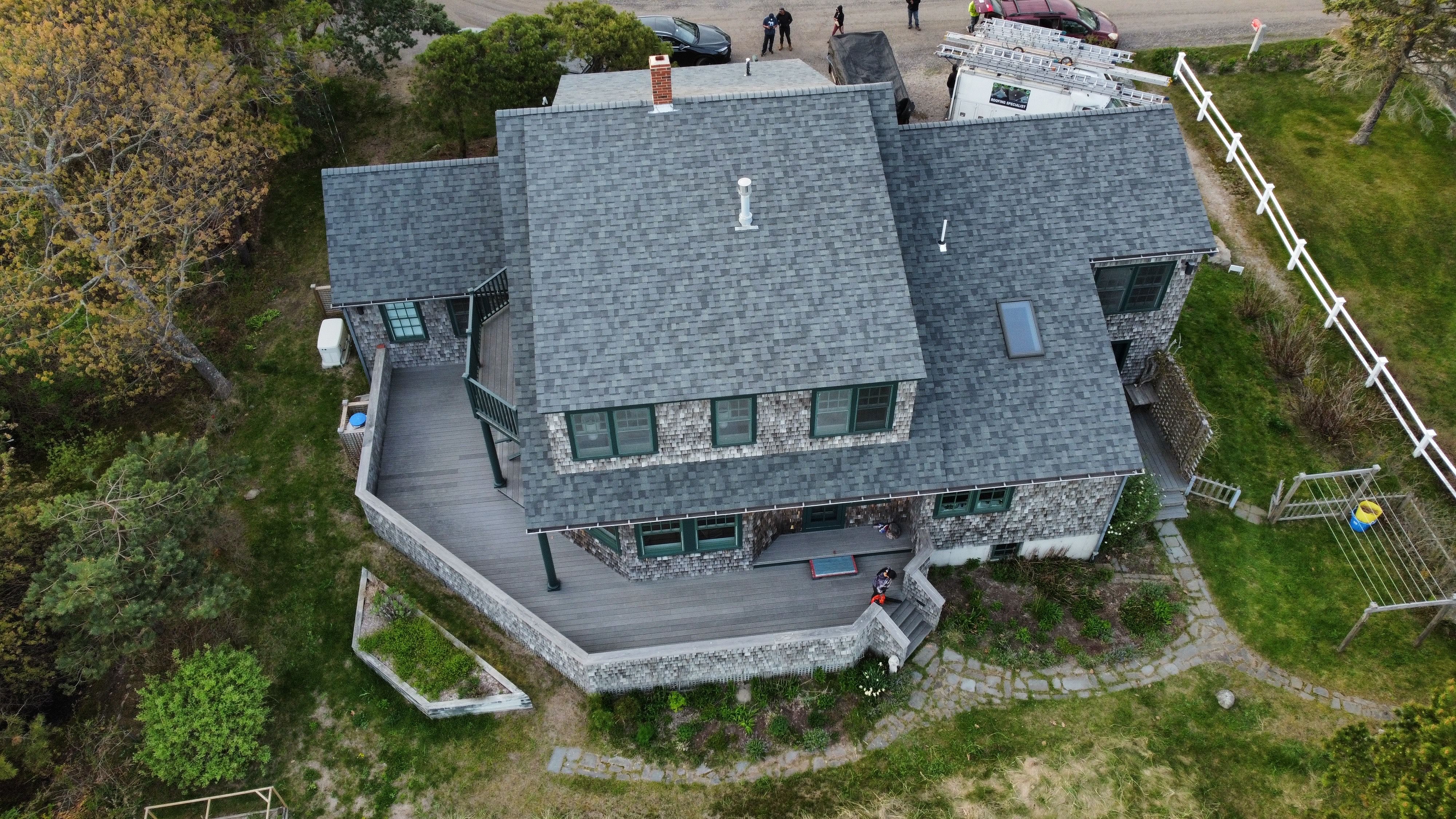 A new gray shingle roof on a blue colonial with a red door