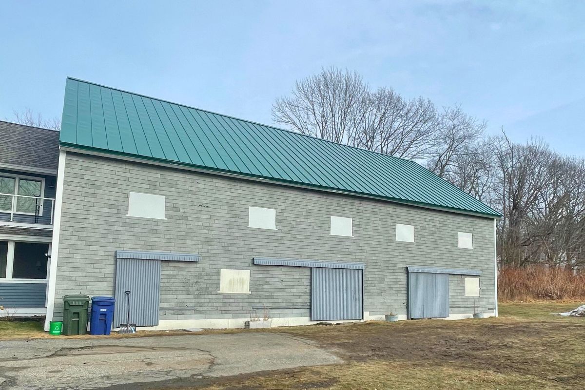 A green standing seam metal roof on a long stone building